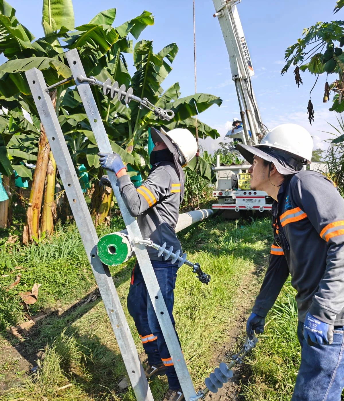 Técnico de SIEEC con equipos de protección personal instalando cruceta metálica y aisladores en poste de red eléctrica aérea en Santa Marta, Colombia